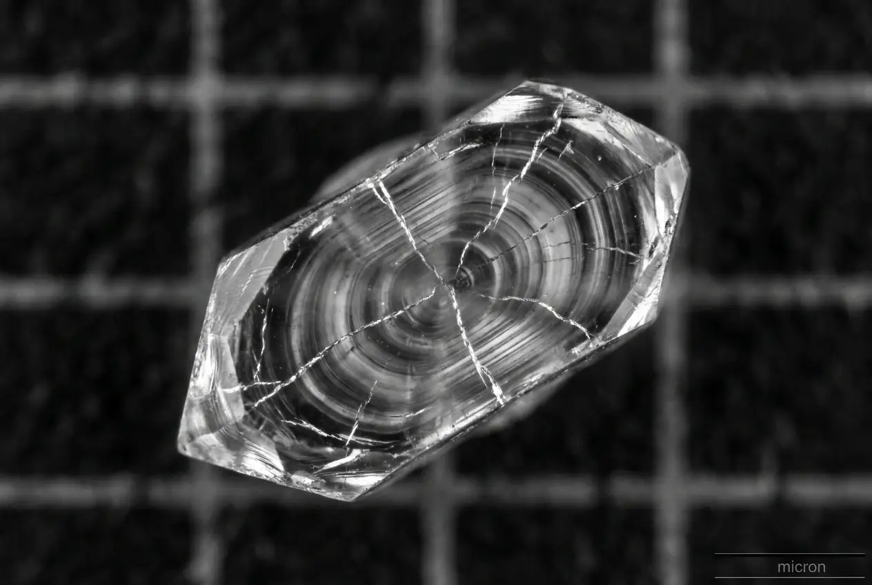 A lunar zircon crystal under the microscope, glowing amber against black